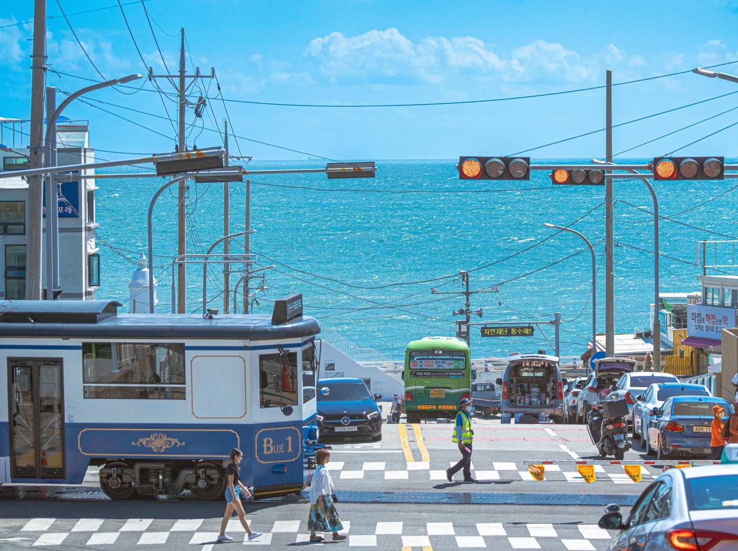 Discover the charm of Busan as you stroll along Haeundae Blue Line Park capturing stunning coastal views and the lively ambiance of local transport and bustling streets. Perfect for memorable photos!